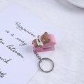 Rosa Mini-Hefter-Schlüsselanhänger mit süßem Braunbären-Anhänger auf weißer Karte - Kirschblütenrosa Süßer Bär