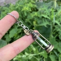 Nahaufnahme eines Retro-Sanduhr-Anhängers mit weißem Sand und graviertem Wish-Anhänger - Stil 7 (Wunsch Anhänger + Sanduhr)