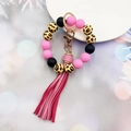 Dettaglio del portachiavi con perline leopardate rosa e nappa su vassoio bianco - Rosa
