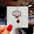 Dynamic basketball enamel pin featuring a red hoop and dangling ball on a display card - 101*Basketball Hoop with Ball Pin