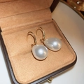 Detalle macro de elegantes pendientes de perlas con ganchos dorados en caja de cuero - 62# Perla gota blanca