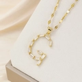 Makro-Detail einer goldenen Buchstaben-G-Halskette mit Zirkonia-Steinen im Baguetteschliff - Buchstabe G Stil