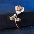 Detailed close-up of a gold rose brooch with white enamel petals and a pearl accent - White Rose