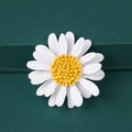 Macro shot of white enamel daisy brooch with yellow center on dark green background - Daisy - White (Matte)