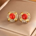 Macro detail of gold stud earrings with a red textured stone and sparkling rhinestones - Round Rhinestone / Gold + Red Turquoise
