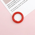 Macro detail of a red round metal spring ring buckle on a soft pink surface - Red