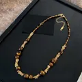 Collier en œil de tigre plaqué or 18 carats avec dimensions sur support de présentation - 77# Collier Oeil de Tigre Enroulé de Fil Doré Café