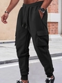 Detail of men's black waffle texture cargo pants with side pockets in a street setting - S / Black