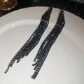 Dettaglio di eleganti orecchini lunghi con nappe di strass neri in un vassoio - Nero