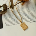 Collana con ciondolo quadrato lettera L dorata con catena a fune su libro vintage - Lettera L Oro