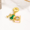 Macro shot of gold pendant featuring a pink enamel camera and green globe charm detail - Photography - Pink Camera (ZYN-DME896G-1)