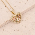 Close-up of golden heart pendant with colorful gemstones and zircon inlay on stone surface - Hollow Flower Heart