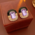 Close-up of vintage gold earrings with black enamel, purple gem, and white rhinestones - Black Gold Vintage Purple Gemstone Style / Gold-Black-Purple