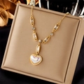 Collar dorado con colgante de corazón, perlas y cristales en exhibidor de terciopelo beige - Dorado