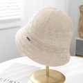 Detailed view of a breathable ivory knitted bucket hat with gold metal label decoration - Beige