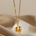 Vista macro del ciondolo a cuore dorato con zircone su sfondo di seta champagne - Cuore Irregolare Zirconia