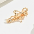 Close-up of golden butterfly hair clip with white oval gem and sparkling rhinestones - Gold Bowknot