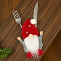 Close-up of Christmas gnome cutlery holder with red knitted hat on dark wood table - Heart Style
