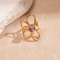 Macro detail of golden flower ring with purple zircon stone on stone texture background - Gold Flower