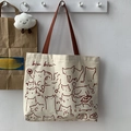 Detail of canvas tote bag featuring cute cat illustrations and reddish-brown straps - Beige Cat