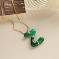 Dettaglio macro del ciondolo lettera Z verde con bordo dorato e catenina sottile d'oro - Lettera Z