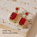 Detailed view of gold copper earrings with red emerald-cut zircon and white gems - Ruby Stud Earrings