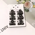 Set of six small black bow-knot hair claws displayed on a decorative jewelry card - Solid Black Clover