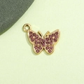 Vista macro di ciondolo a farfalla con strass rosa e base in lega dorata su sfondo verde - Farfalla Viola Chiaro Placcata Oro UV