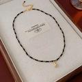 Detail van bohemien ketting met zwarte kralen en gouden ananashanger op een dienblad - Ketting-Zwart-Wulk