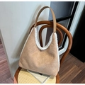 Detailansicht der braunen Wildleder-Schultertasche mit weißem Plüschbesatz auf einem Stuhl - Khaki