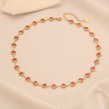 Elegant gold necklace with pink heart gemstones on soft beige fabric background - Pink