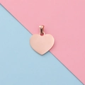 Macro detail of rose gold heart pendant with polished mirror finish on pink and blue background - Rose Gold