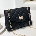 Elegant black quilted crossbody bag with golden chain and white butterfly buckle detail - Black