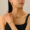 Detailed close-up of a high-polish gold geometric necklace and jewelry set on model - Gold Jewelry Four-Piece Set / Gold