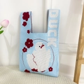 Detail of light blue knit tote bag with a cartoon duck pattern and white DUCK text - Blue Dancing Duck Bag