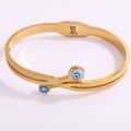 Detail of gold evil eye cuff bracelet with sparkling rhinestones on white background - Gold Cross Eye Open Bangle