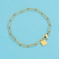 Detail of a gold paperclip link chain bracelet with square tag and lobster clasp on blue - 18K Gold / 15CM
