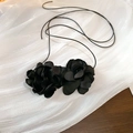 Vista detallada de dos flores de rosa de satén negro en un collar largo minimalista - Flor Negra