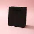 Minimalist matte black paper jewelry gift bag with woven rope handles on a lilac surface - 12x11x6cm / Black