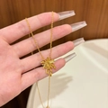 Close-up detail of a gold plated palm tree pendant necklace worn by a model - Gold Necklace