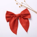 Detailed close-up of a red linen bow hair clip on a clean white background with dried flowers - Red
