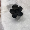 Primer plano de pinza para el cabello de flor negra mate con cinco pétalos sobre blanco - Negro
