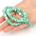 Detailed view of green and white irregular shell bead jewelry held in hand - Irregular Green