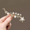 Golden butterfly hair clip with stars and pearls held to show detailed jewelry shine - Gold Star