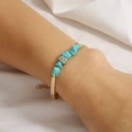 Detail view of handmade gold chain bracelet with irregular turquoise stones on a wrist - Turquoise Gravel (Bar Style)