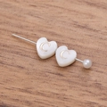 Macro shot of heart-shaped shell pin with letter C and pearl on wood texture - Letter C