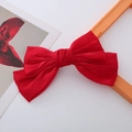 Makroaufnahme der roten Satin-Schleife für Haare auf einem sauberen weißen Hintergrund - Rote Perle Glanz Schleife Federclip