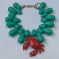 Detailed shot of ocean style necklace with cyan beads and a vibrant red crab pendant - Green Crab