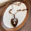 Dettaglio del ciondolo a cuore in legno con croce in metallo e frange su cordoncino - Ciondolo Cuore Croce (Corda con Nappine)