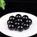 Perle tonde in pietra occhio di gatto nera lucida su piatto bianco, set decorativo - Agata nera